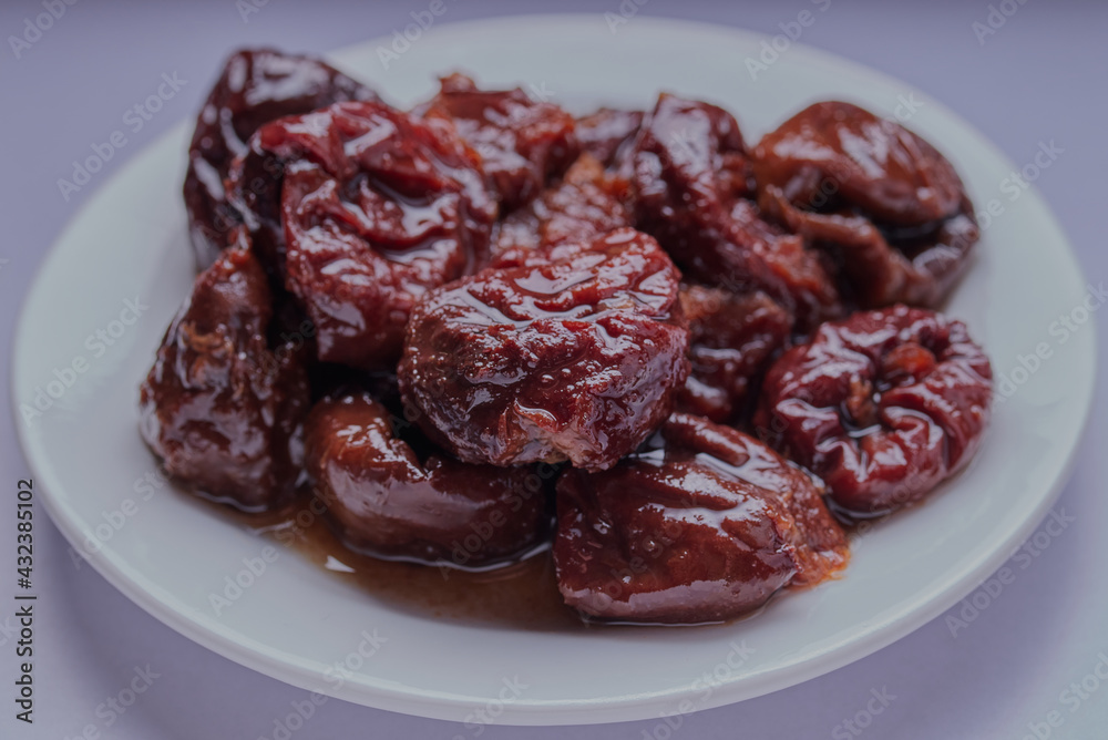 Prunes in juice on a plate.