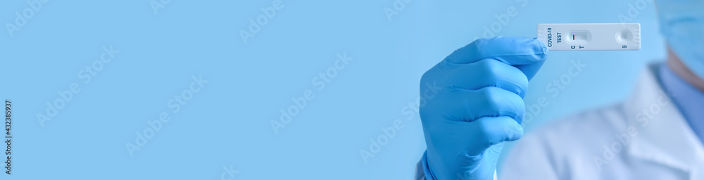 A doctor or nurse wearing a protective mask and gloves shows a rapid laboratory test for COVID-19 to detect IgM and IgG antibodies to the new coronavirus. The test shows a negative result. Diagnosis