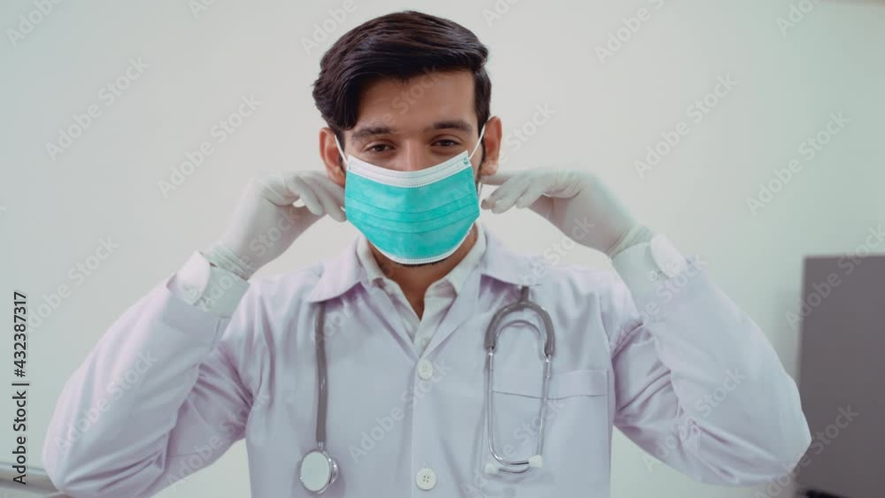 Young doctor putting on face medical mask against virus bacteria prevention outbreak on light background. Health protection Corona Virus concept, Covid-19, Health care, close up portrait, 4k footages