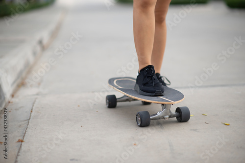 Closeup Asian woman playing on surfskate or skateboard in the street