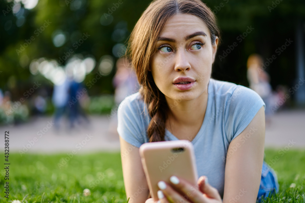 Contemplative woman holding digital smartphone in hands thoughtful looking away during free time, pondering Caucasian hipster girl with modern cellphone device thinking about online blogging