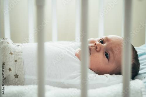 Close Up Photo of Adorable Baby Lying in Crib. Adorable newborn baby boy lying in bed at home.