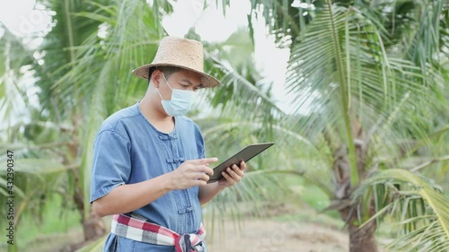 Thai gardeners wear a mask to protect against the virus covid-19 Intentionally reading news on the tablet screen in the garden, the concept of follow-up on coronavirus-19 and the economy