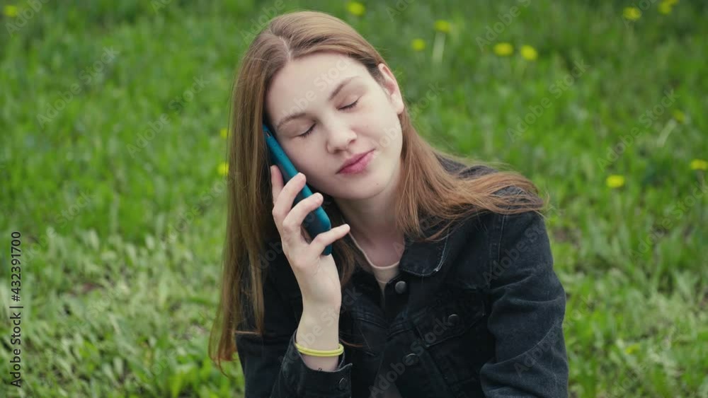 Portrait of happy young beautiful woman sitting in the spring park on the grass and talking on a mobile phone. Portrait of happy young beautiful woman sitting in the spring park on the grass and talking on a mobile phone.