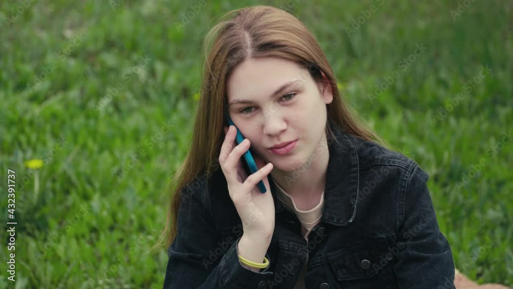 Portrait of happy young beautiful woman sitting in the spring park on the grass and talking on a mobile phone. Portrait of happy young beautiful woman sitting in the spring park on the grass and talking on a mobile phone.