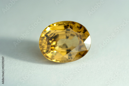Natural genuine yellow color zircon oval faceted loose gemstone setting for jewelry making. Mined in Cambodia. White paper background.