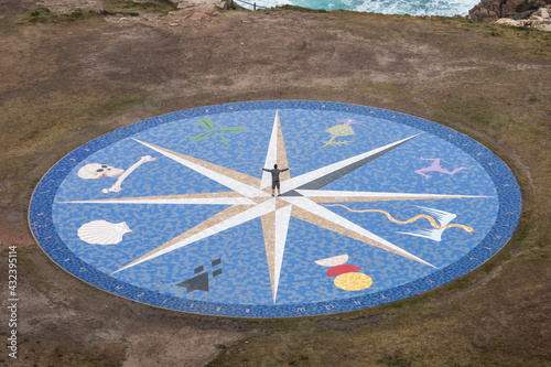Man posing in the center of a compass rose showing the Celtic nations at the Hercules lighthouse at La Coruna, Galicia, Spain