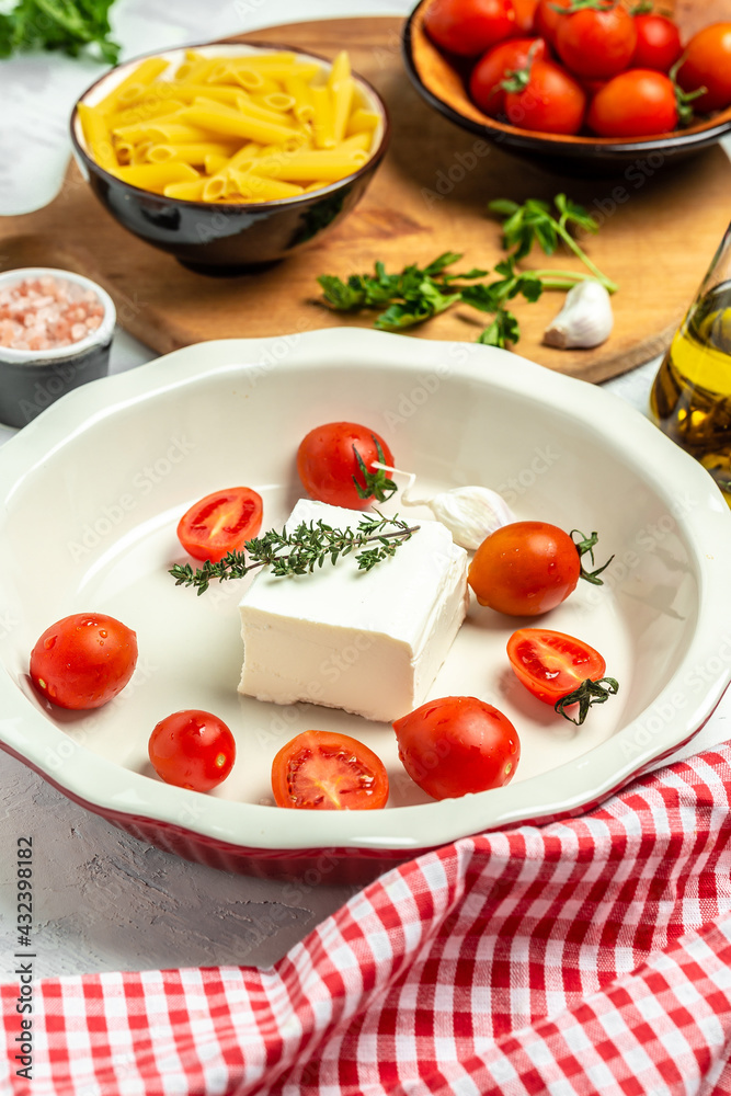 Preparation of ingredients for trending feta pasta with cherry tomatoes herbs and garlic, vertical image, top view Preparation of ingredients for trending feta pasta with cherry tomatoes herbs and garlic, vertical image, top view