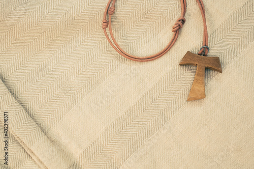 Closeup shot of a wooden tau cross necklace on a wooden background