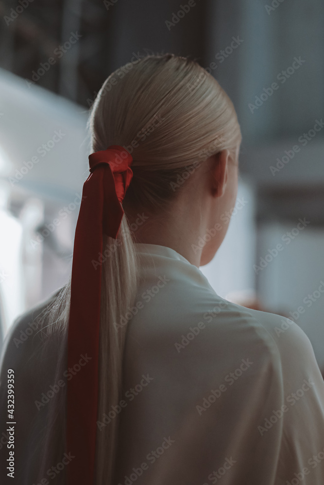 Female hairstyle of blonde hair elegant ponytail with red ribbon. Back view  Stock Photo