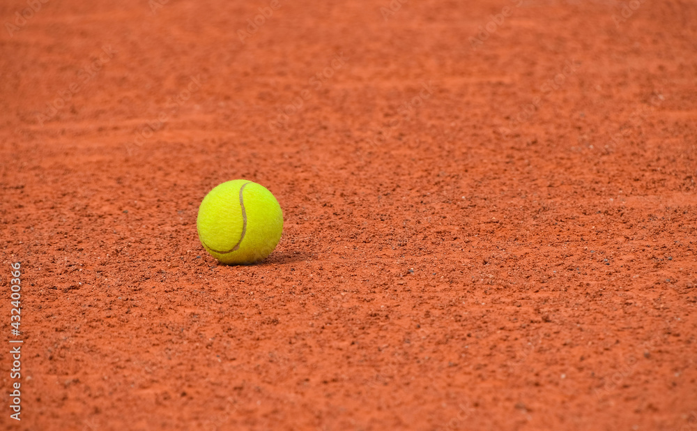 Yellow tennis ball on red clay ground court