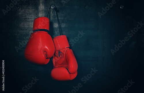 Red leather boxing gloves hanging on black wall © breakingthewalls