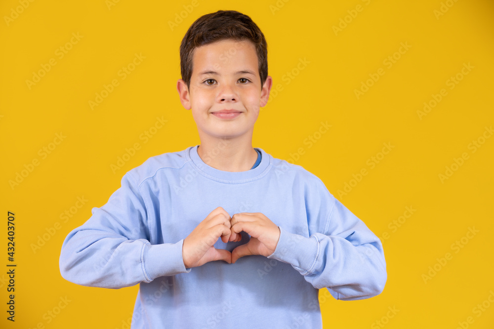 Little boy wearing casual clothes smiling in love doing heart symbol shape with hands. romantic concept. Little boy wearing casual clothes smiling in love doing heart symbol shape with hands. romantic concept.