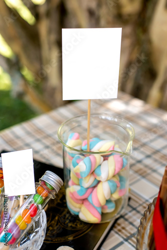 Jar with colorful marshmallows on decorated birthday table.