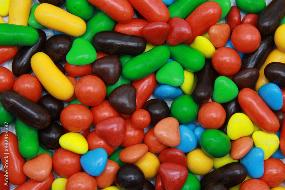 Bright rainbow background of small round candies of different shapes in a hard glaze. Many colorful close-up lollipops are sold by weight.Flat layout Bright rainbow background of small round candies of different shapes in a hard glaze. Many colorful close-up lollipops are sold by weight.Flat layout