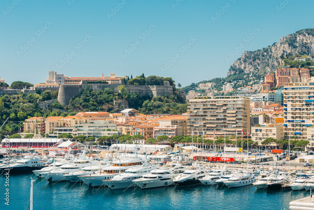 White Yachts Of Different Sizes Are Moored At City Pier and Royal palace on background in Monte Carlo, Monaco