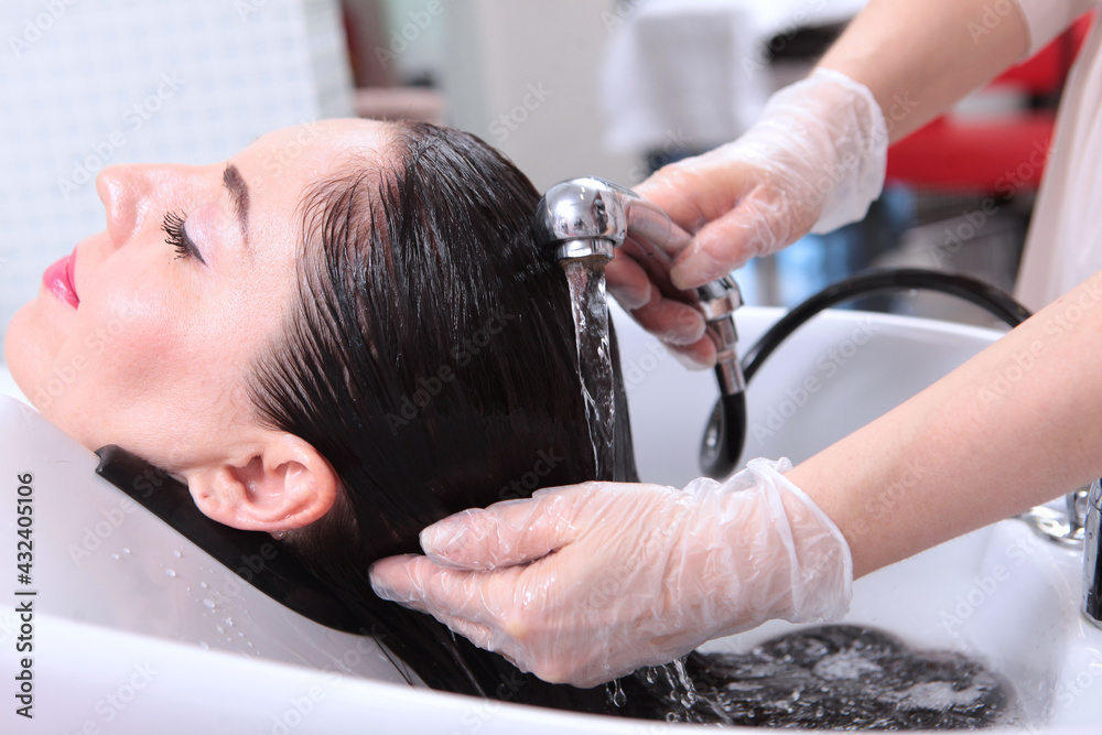 A beauty salon client washes her hair. Hair under running water.Wet, long hair. Spa treatments for hair. The barber washes the client's hair. A beauty salon client washes her hair. Hair under running water.Wet, long hair. Spa treatments for hair. The barber washes the client's hair.