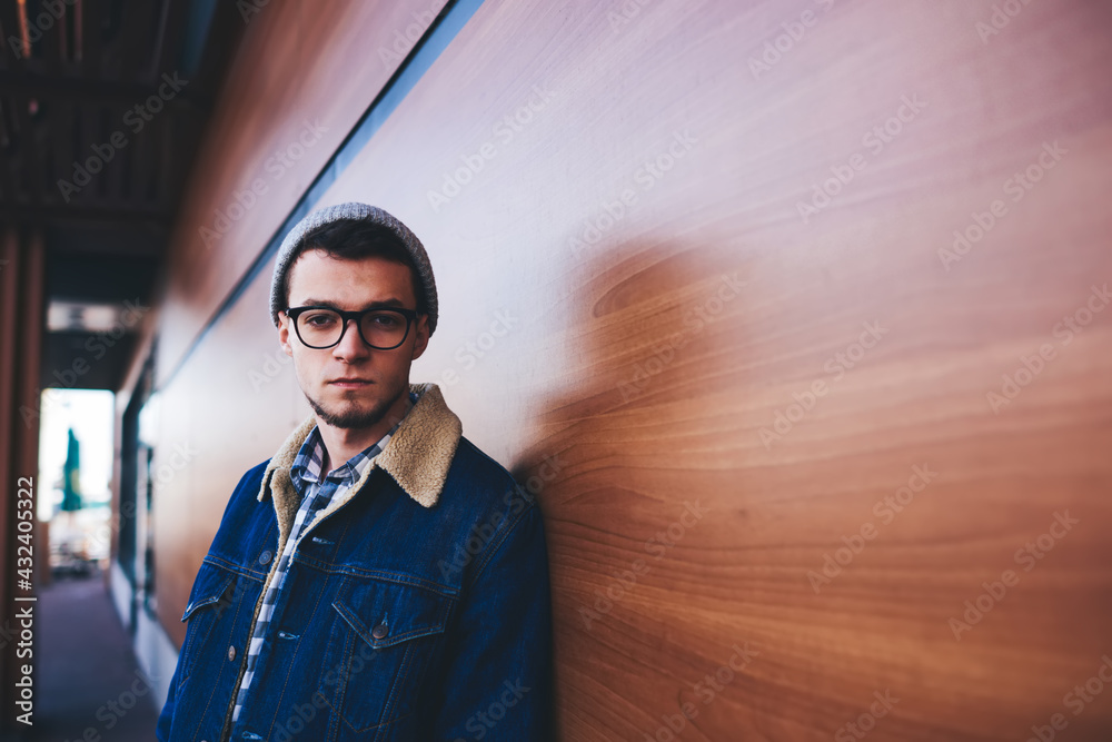 Unemotional man with eyeglasses near wooden wall Unemotional man with eyeglasses near wooden wall