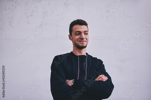 Smiling man folding hands near white wall