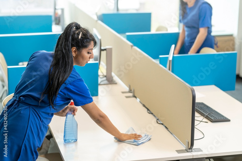 Cleaners clean the desks in the office space.Cleaning services