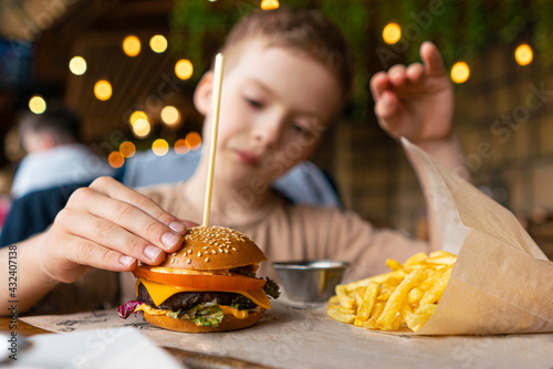 a child in a cafe eats a mini burger with fries. children's menu