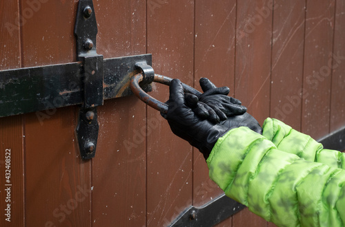 Fotografie a child in black leather gloves tries to open the door behind an iron ring