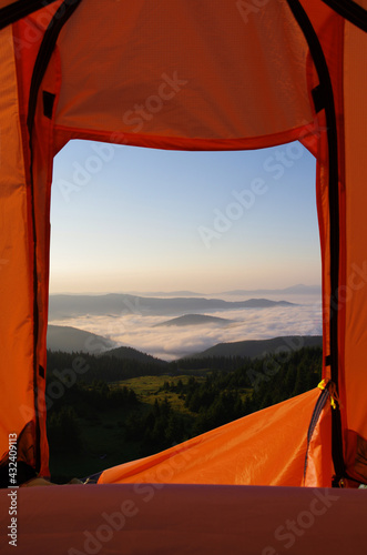 orange camping tent to the high mountains, forest, bright sky