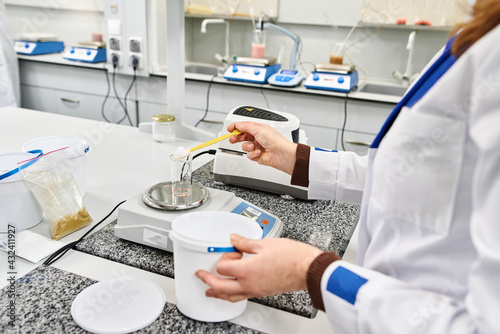 the hands of a laboratory worker sprinkle the drug on the scales with a spoon