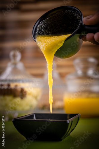 Fotografi Ghee being poured to a small container and ready to be served.