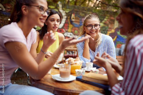 A group of female students are listening to a female friend telling a story in the bar's garden. Leisure, bar, friendship, outdoor