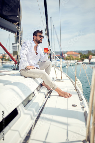 A young man is enjoying a coffee while sitting on a yacht at sea. Summer, sea, vacation © luckybusiness