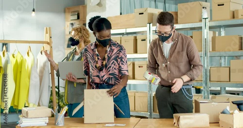Mixed-race people working at storehouse preparing parcels packing ordered clothes for shipment. Woman employee browsing on laptop making inventory. Fashion shop. Clothing business. Job concept