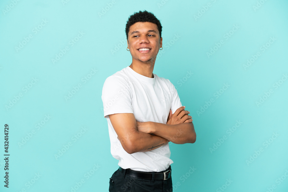 Young African American man isolated on blue background with arms crossed and happy Young African American man isolated on blue background with arms crossed and happy
