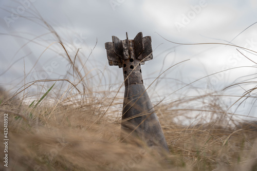 Foto An unexploded rusty mortar mine poses a hazard in withered grass on a cloudy spr