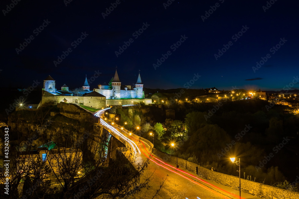 Obraz premium View on the Kamianets-Podilskyi castle in the night. Beautiful stone castle on the hill at night. Long exposure. Illumination of the castle. Ukraine