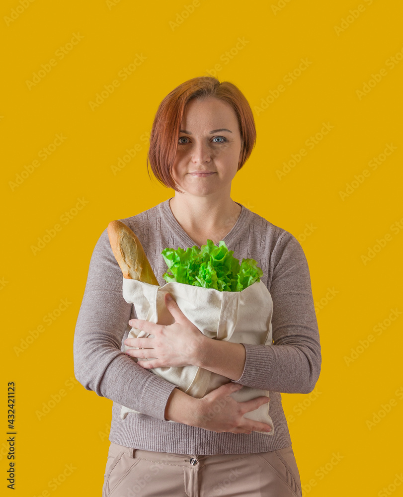 a grocery bag with bread and herbs in the hands of a woman on a yellow background a grocery bag with bread and herbs in the hands of a woman on a yellow background