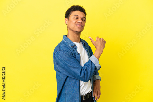 Young African American man isolated on yellow background proud and self-satisfied