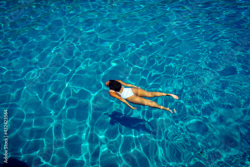 young woman dives through crystal clear waters in greece