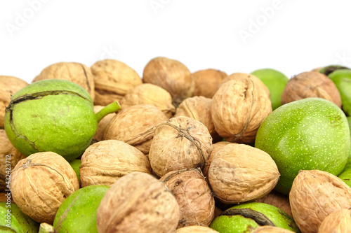 Walnut fruits closeup. Heap of walnuts in wooden shell with green pericarp on white