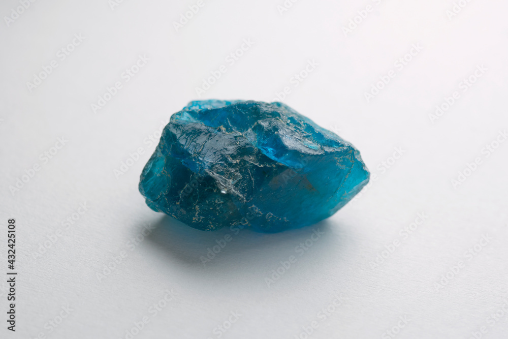 Natural mined raw rough blue color apatite translucent crystal gemstone. Can be polished or faceted. For making jewelry or collection. Light gray gradient background. Gemology theme.