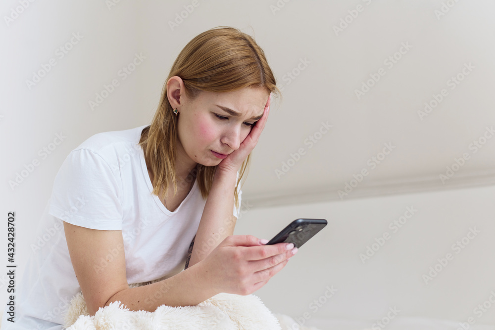 Unhappy depressed caucasian woman crying , while suffering from grief or break up with boyfriend in phone. Broken heart, sitting on bed at home concept Unhappy depressed caucasian woman crying , while suffering from grief or break up with boyfriend in phone. Broken heart, sitting on bed at home concept