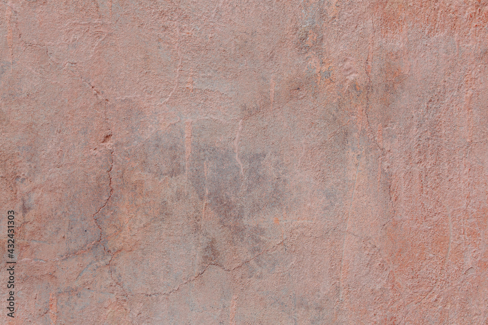 A pink-yellow fragment of a concrete wall with a copious amount of scratches. Rough surface with scuffs and cracks.