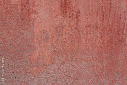 A pink-yellow fragment of a concrete wall with a copious amount of scratches. Rough surface with scuffs and cracks.