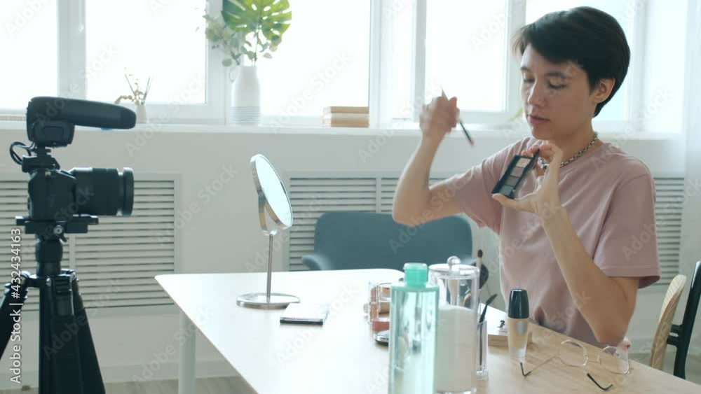 Professional make-up artist is recording video for internet vlog applying cosmetics sitting in room at home. Modern technology and blogging concept. Professional make-up artist is recording video for internet vlog applying cosmetics sitting in room at home. Modern technology and blogging concept.