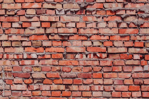 Old shabby wall with elements of destroyed bricks. Can be used as background for design or poster. Red brick background.