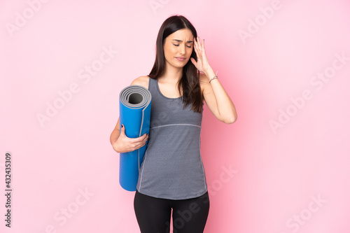 Young caucasian woman with mat isolated on pink background unhappy and frustrated with something. Negative facial expression