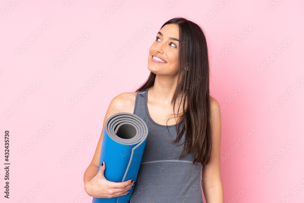 Young caucasian woman with mat isolated on pink background laughing and looking up Young caucasian woman with mat isolated on pink background laughing and looking up
