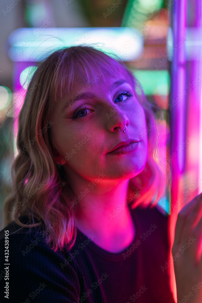 Retrato cercano de chica rubia guapa junto a luces de colores en zona de atracciones de feria