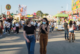 Dos chicas felices paseando por zona de atracciones de una feria