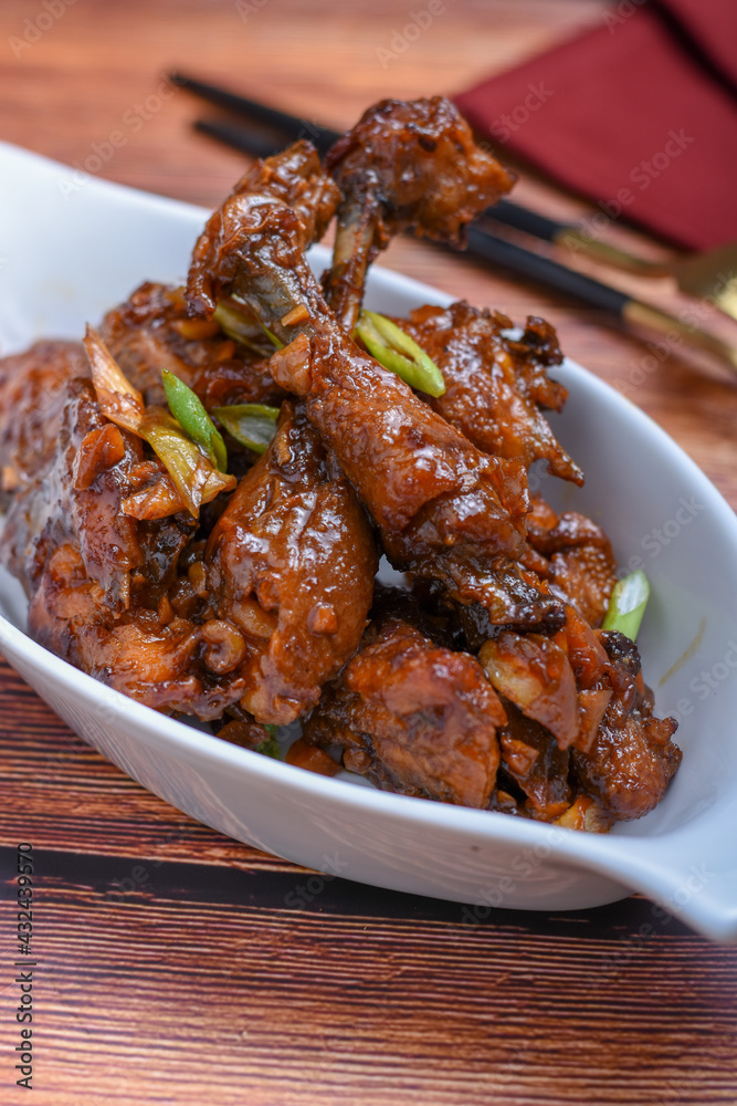 Ayam goreng mentega (fried chicken in buttery sweet soy sauce .on wooden tray.indonesian cuisine Ayam goreng mentega (fried chicken in buttery sweet soy sauce .on wooden tray.indonesian cuisine